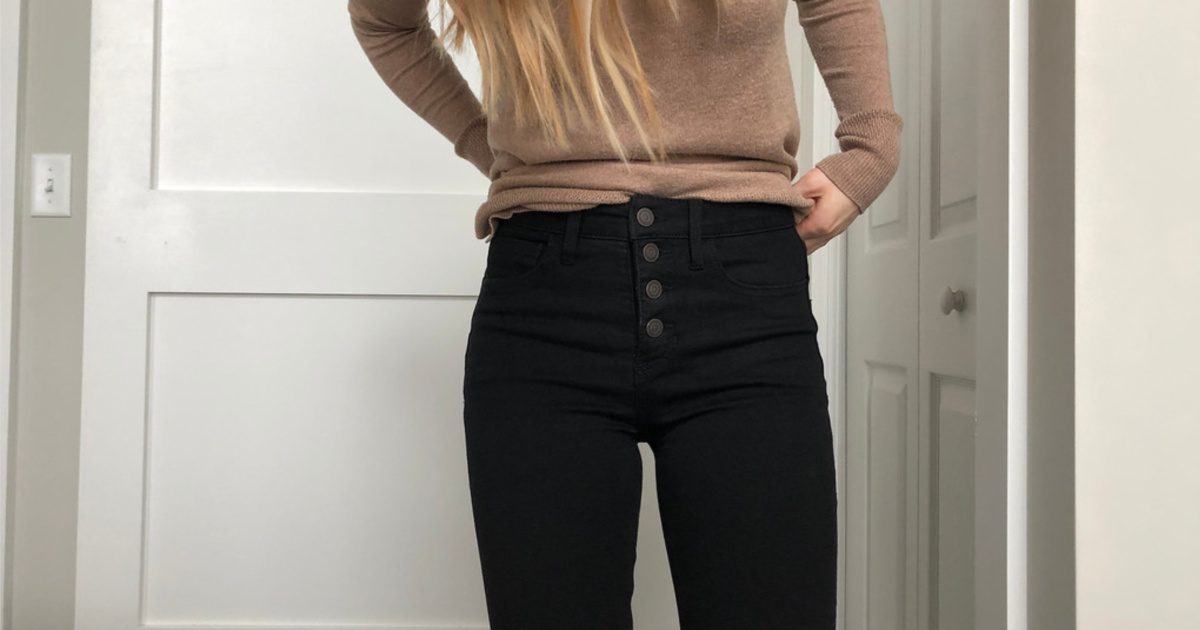 woman wearing brown sweater and black jeans with 4 buttons in front