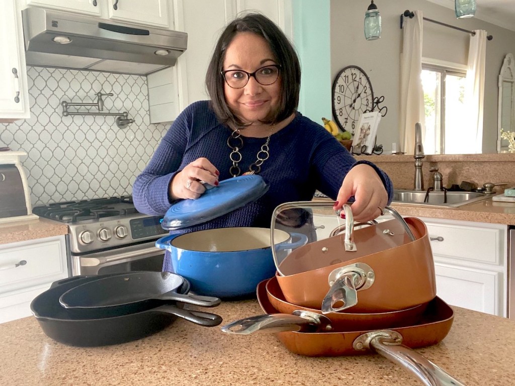 woman showing off various styles and colors of pots and pans