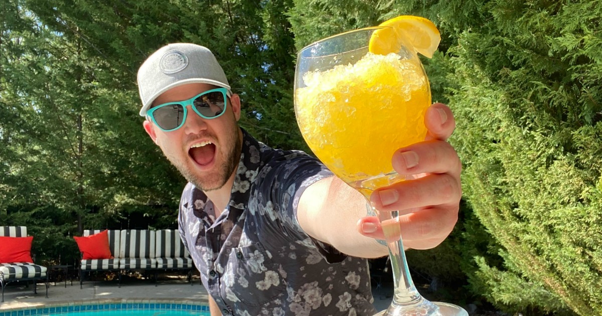 man holding wine glass outside filled with an adult slushie 