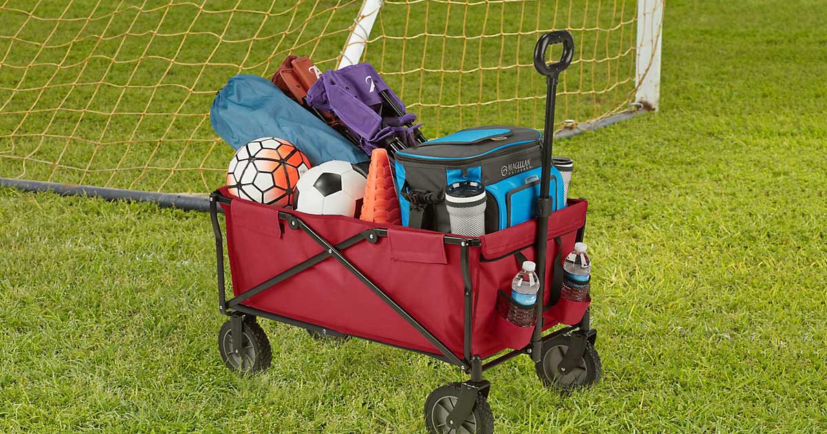 red folding wagon with sports equipment in it on a soccer field