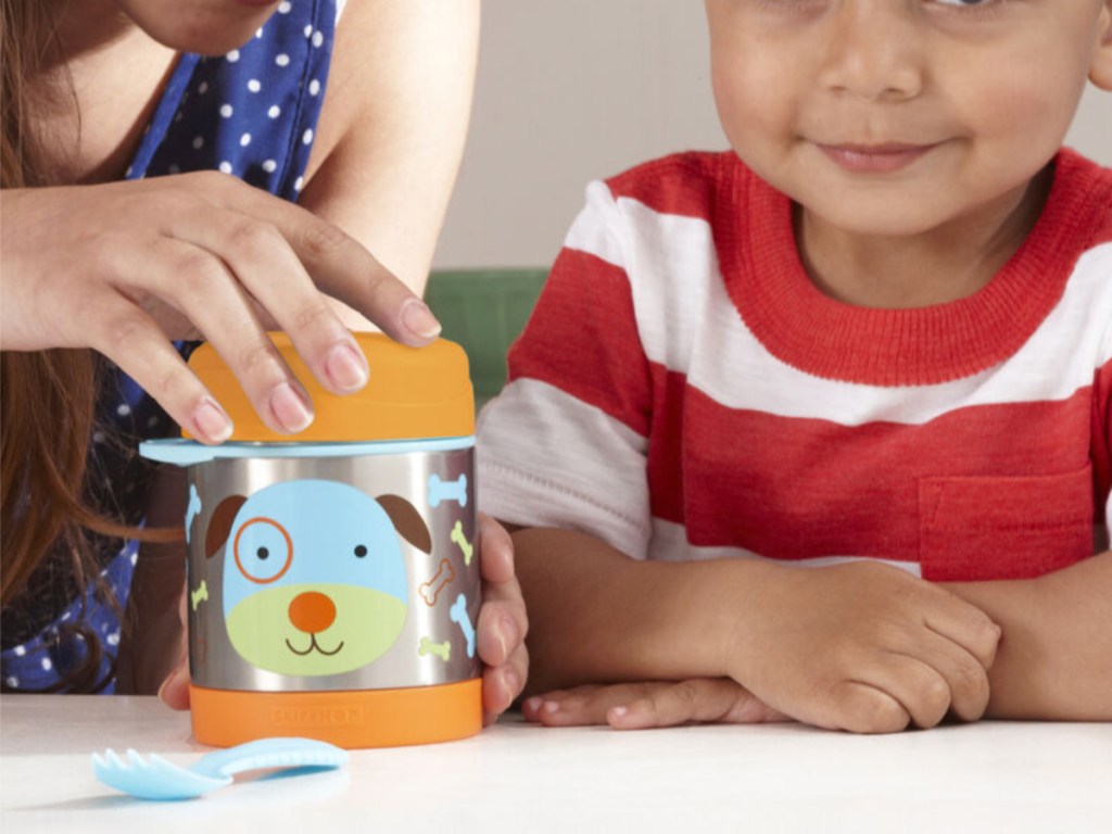 woman's hand securing top on kids food jar with boy sitting next to her