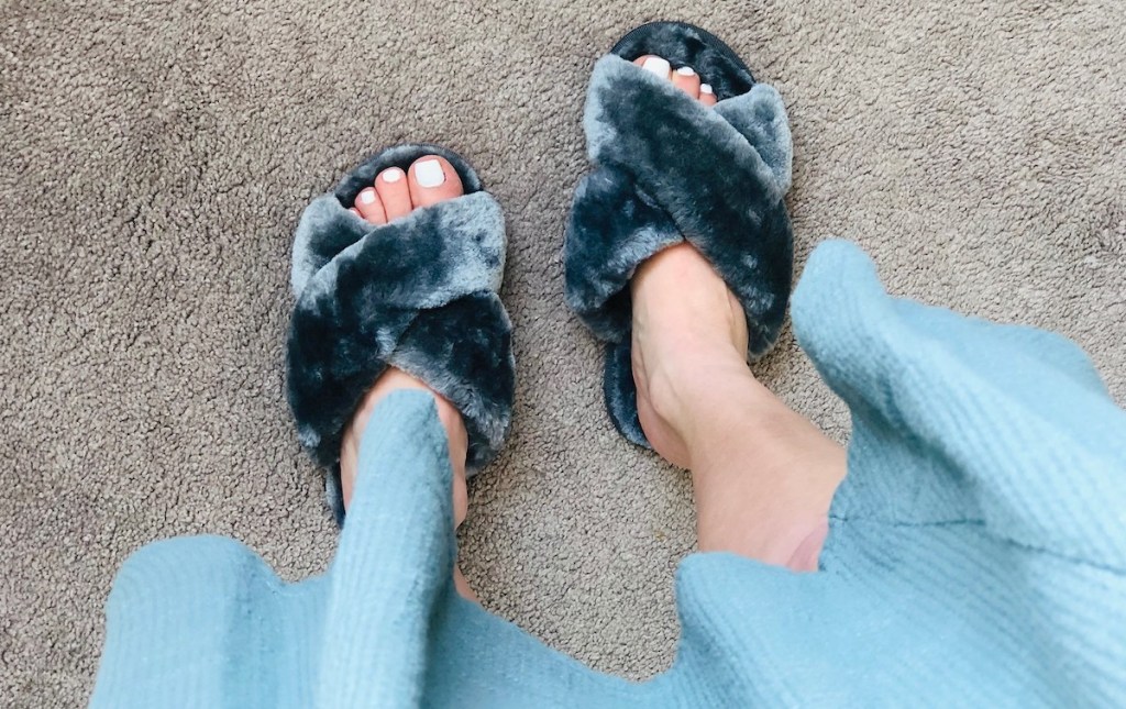 feet wearing dark gray fuzzy slippers with sage green dress at knees