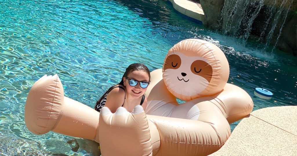 girl wearing sunglasses hanging on sloth pool float in water