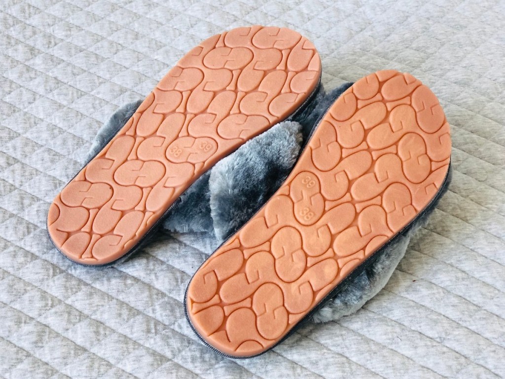 bottoms of slippers laying on quilted light gray blanket