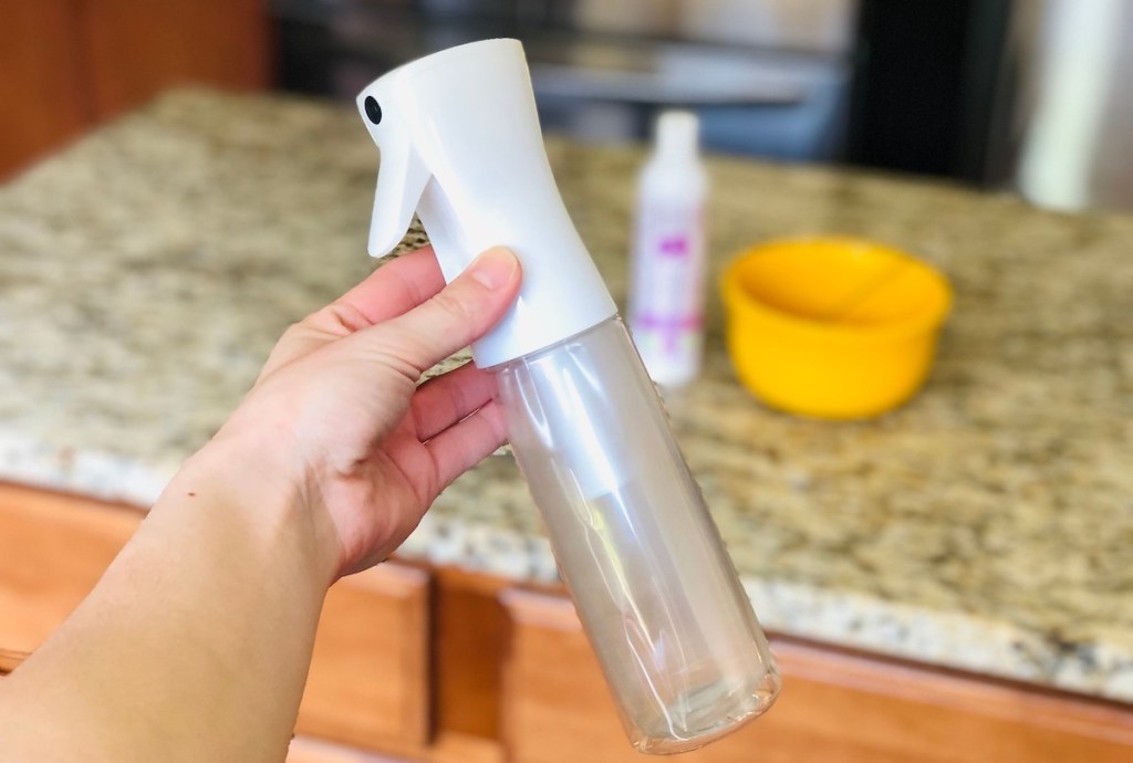 hand holding a clear spray bottle 