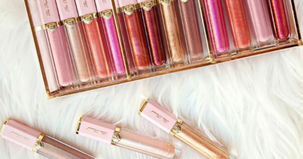 too faced lip glosses in box and on white furry surface