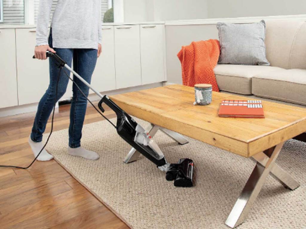 woman vacuuming under her coffee table in a living room