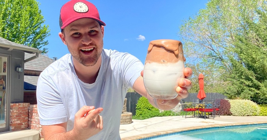 man holding and pointing to a glass filled with milk and whipped chocolate nutella 