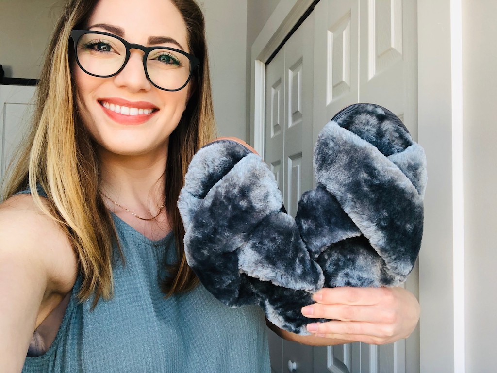woman holding fuzzy grey slippers 
