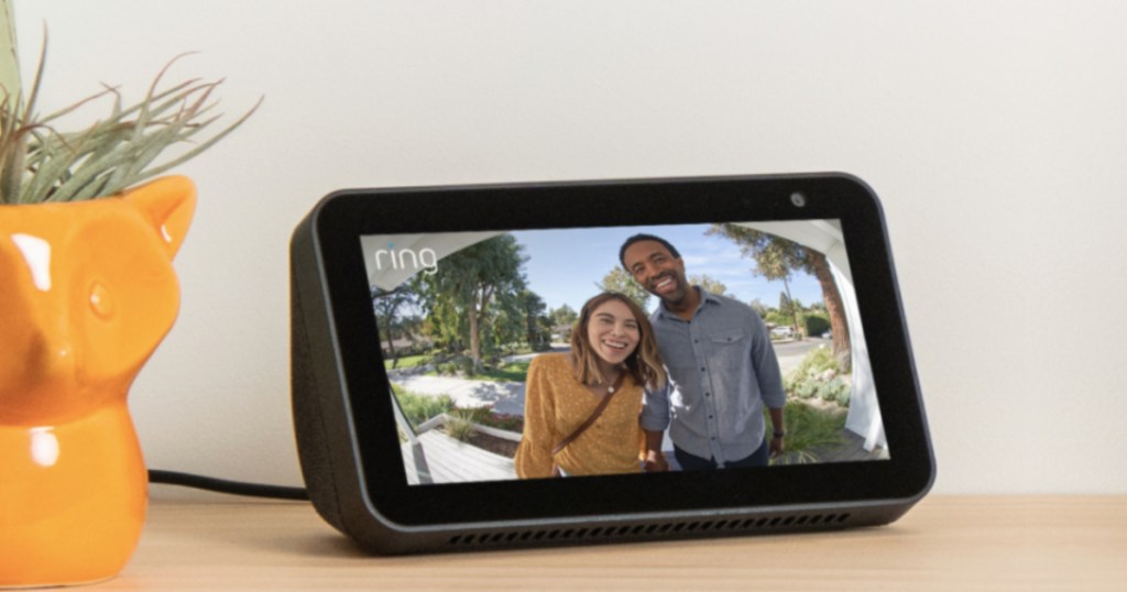 black smart device showing smart camera footage on table next to plant