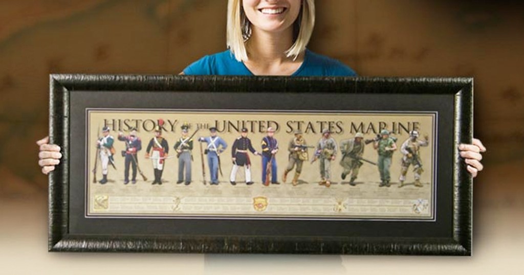 women holding a framed poster of the history of the US marines