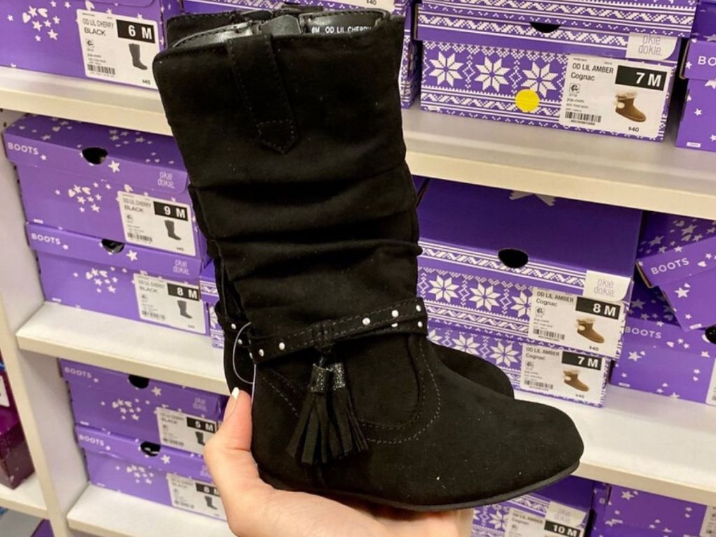 woman's hand holding tall suede kids boots