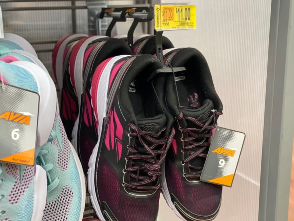 women's black and pink running shoe hanging in store