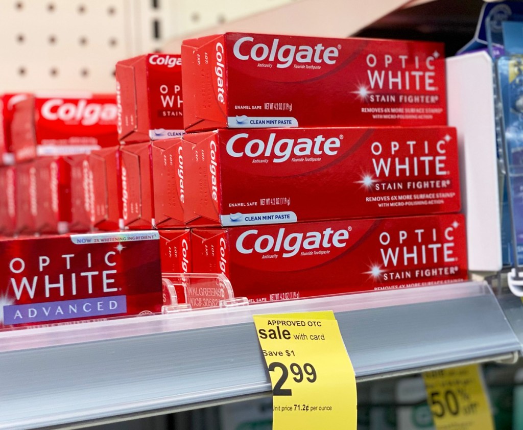 red boxes of colgate optic white toothpaste stacked on a store shelf