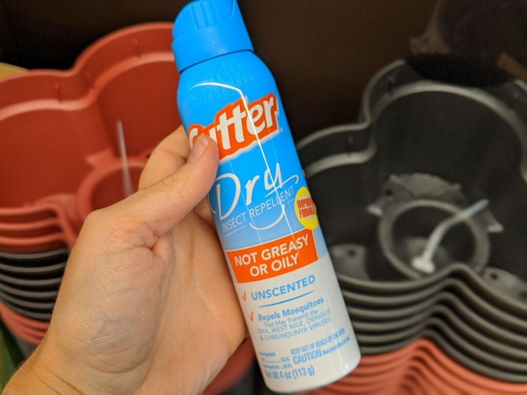 woman's hand holding a bottle of insect repellent spray