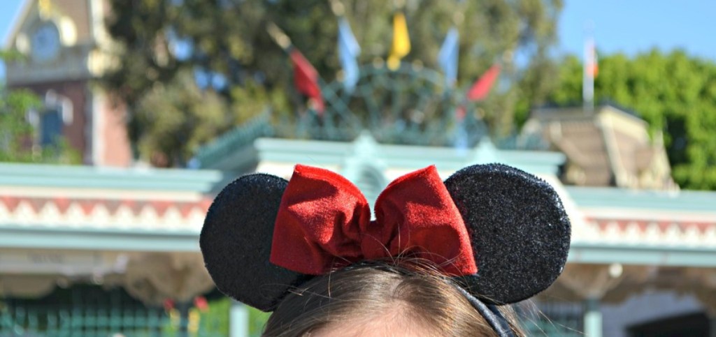 girl with black Mickey Mouse ears and red bow at Disneyland