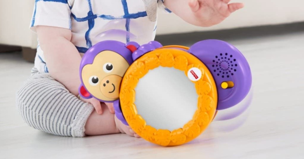 baby sitting on the floor playing with a toy monkey 