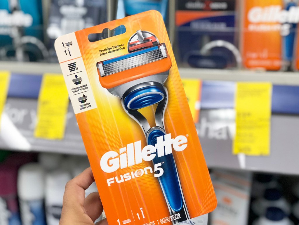 person holding up an orange package for gillette fusion razor in front of razor shelf in store