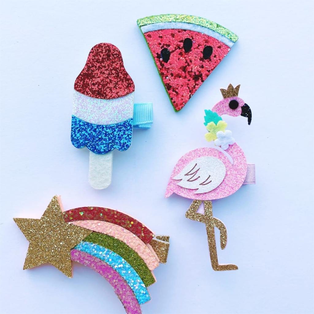 glitter hair clips in the shape of watermelon, shooting star, flamingo, and rocket pop popsicle