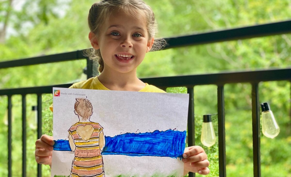 A little girl holding a page colored from a real picture