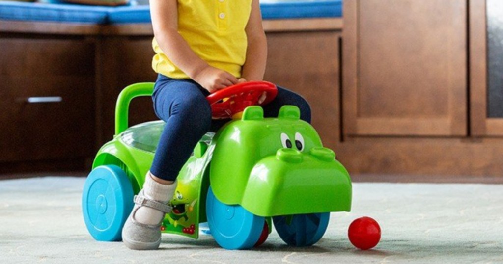 young girl on hippo ride on toy in home
