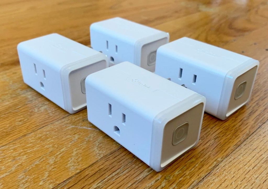 four white smart plugs sitting on wood table