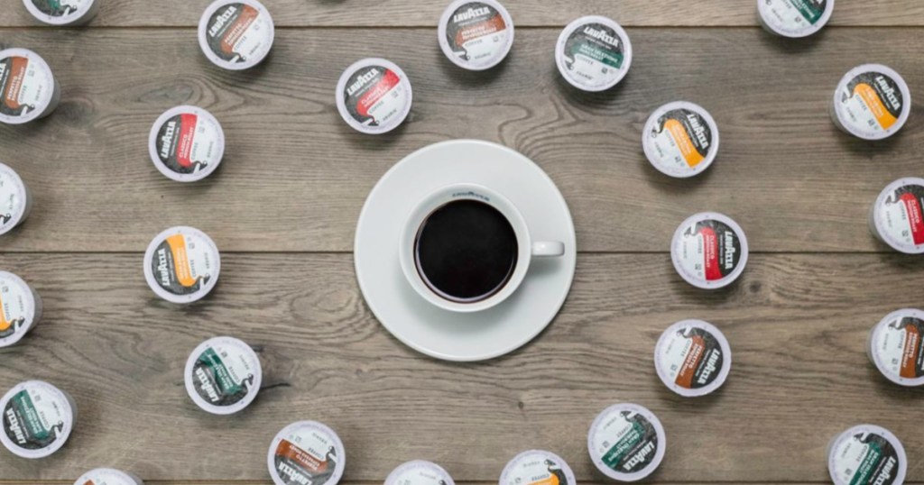 various flavored coffee pods surrounding cup of coffee on wood table