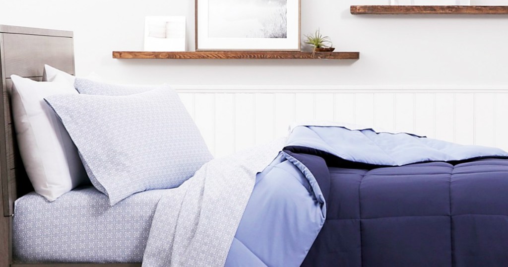 bed with printed sheet set and blue reversible comforter on it