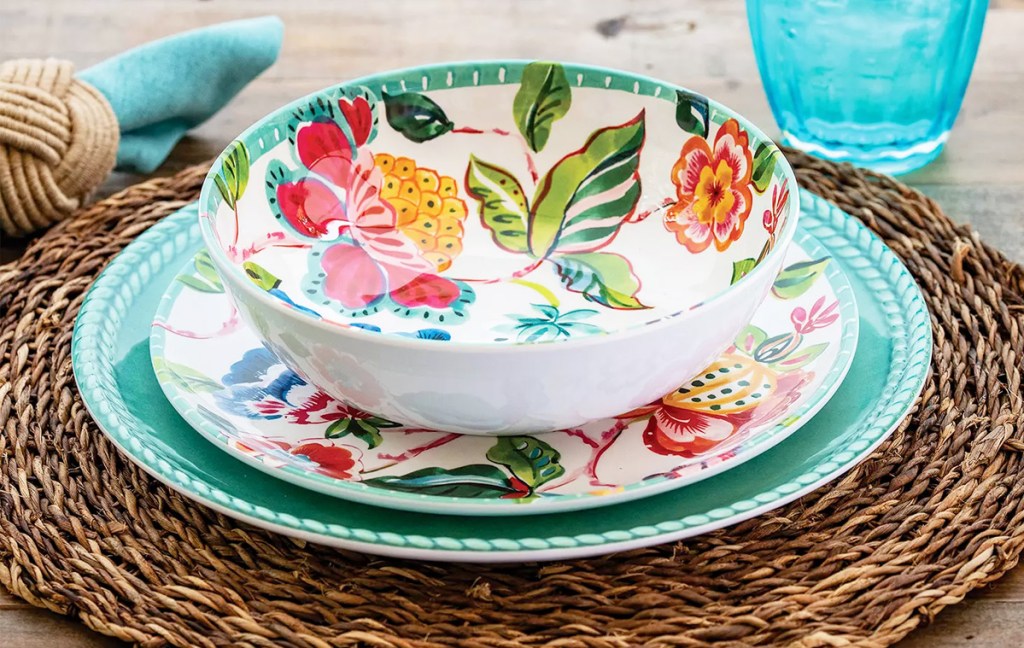 set of floral print bowl and salad plate on top of a solid color turquoise dinner plate on a wicker place mat