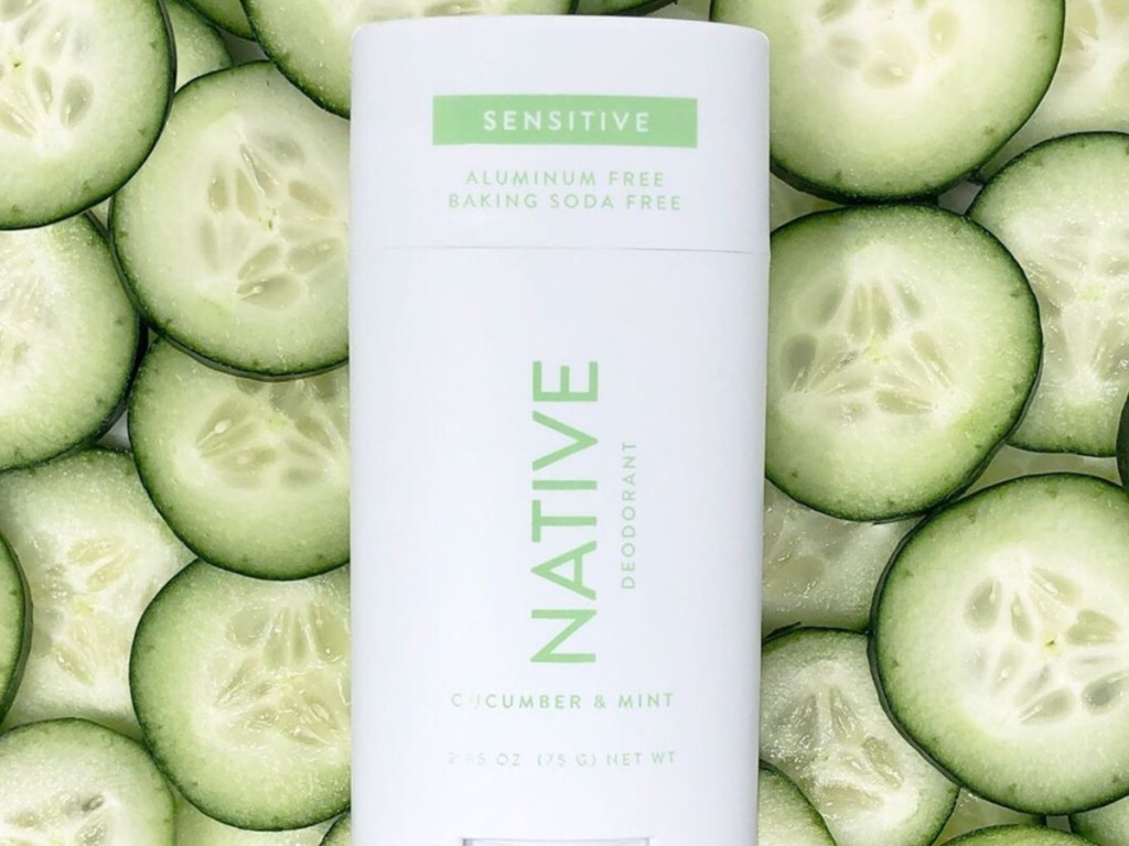 Native cucumber and mint natural deodorant laying on top of fresh cucumbers