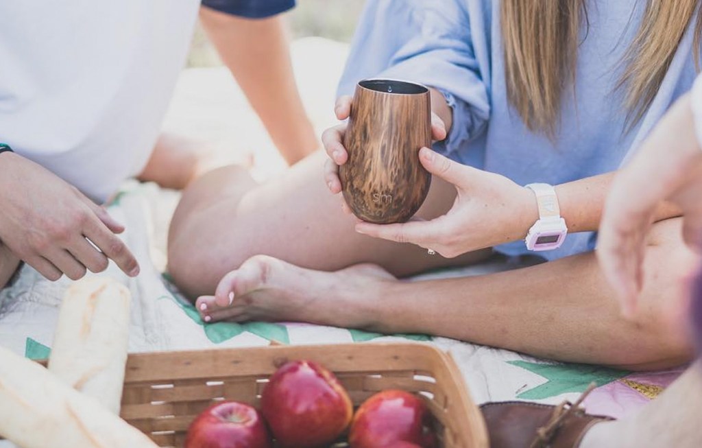person holding a brown wood grain print wine tumbler