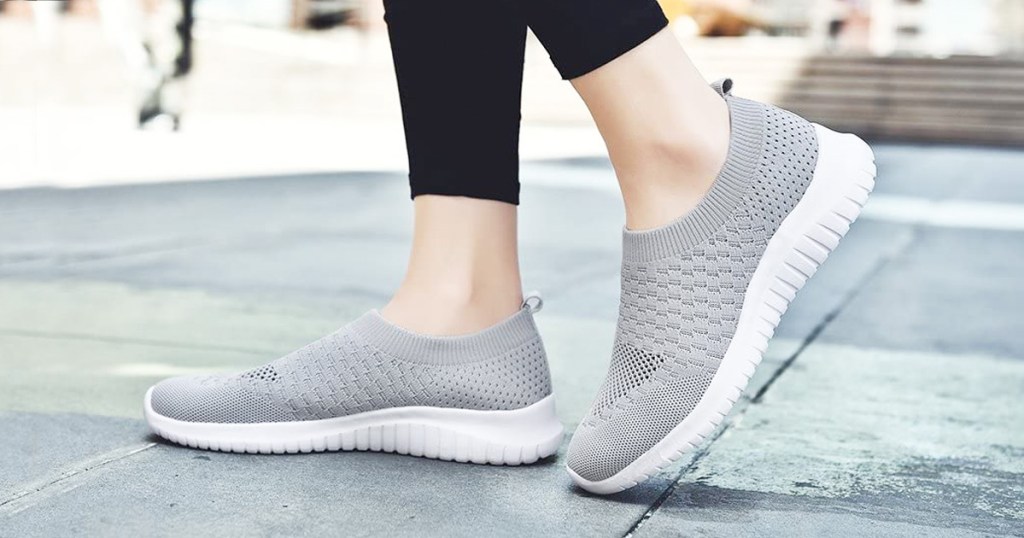 person wearing a pair of light grey slip on shoes with black leggings on concrete outside