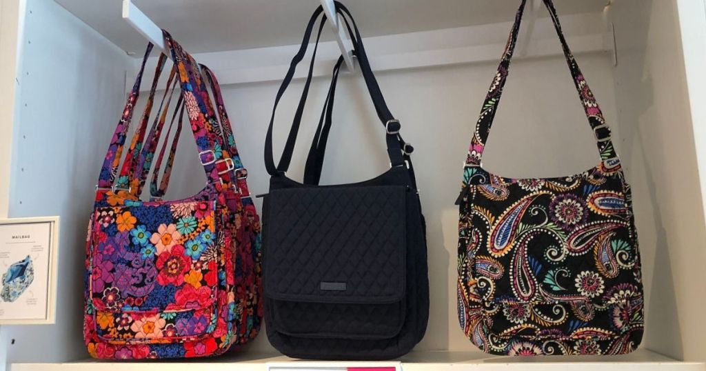 three crossbody bags hanging on a store display