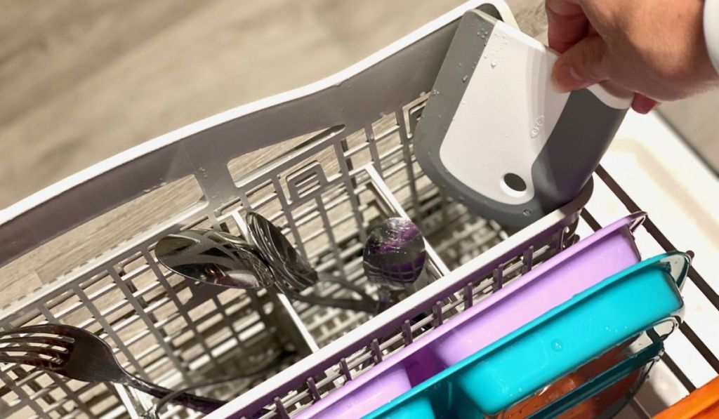 A hand grabbing a oxo squeegee gadget out of the dishwasher