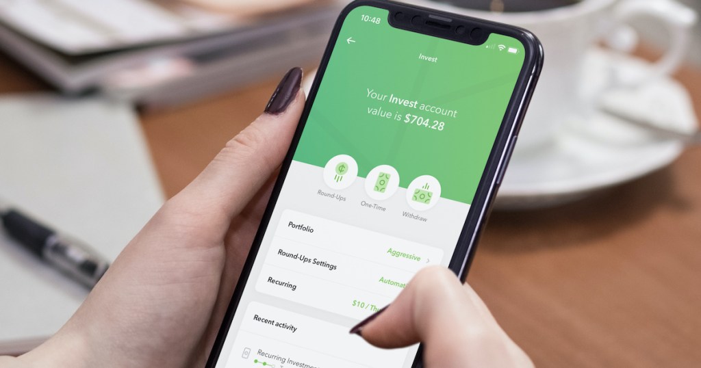 hands holding a phone with acorns investing app on screen best way to save money saving