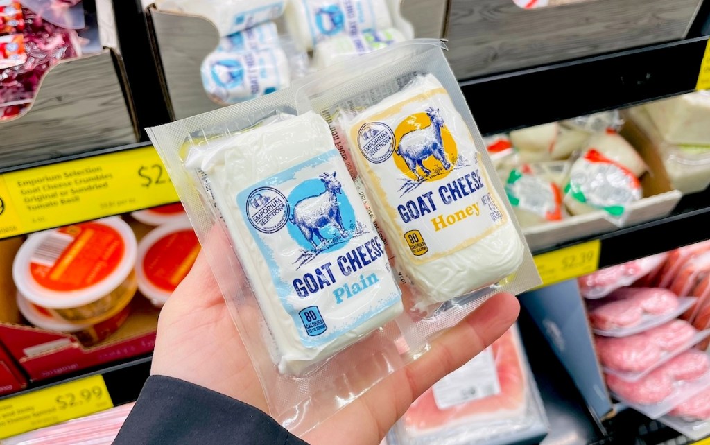 hand holding two packages of goat cheese