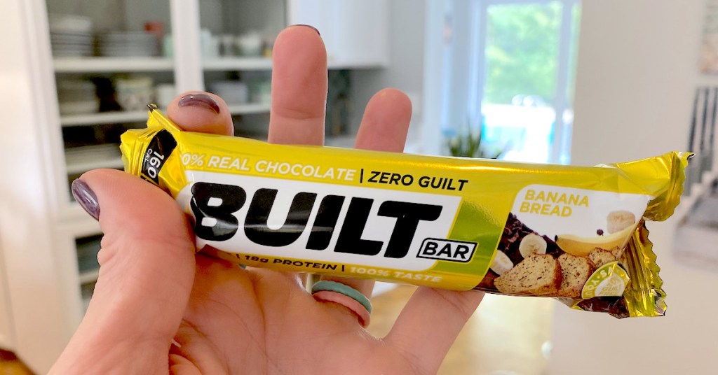 hand holding a yellow banana bread built bar in kitchen