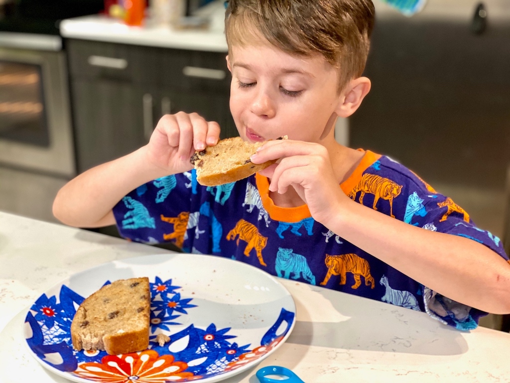 little boy eating homemade bread in kitchen