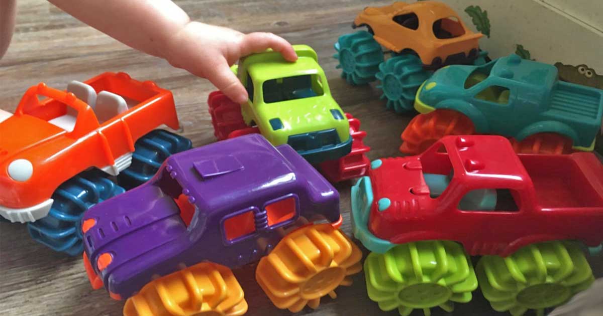 child playing with toy monster trucks on the floor