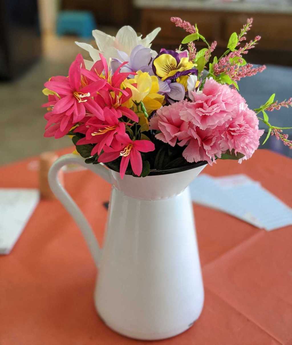 white pitcher vase with colorful faux florals inside