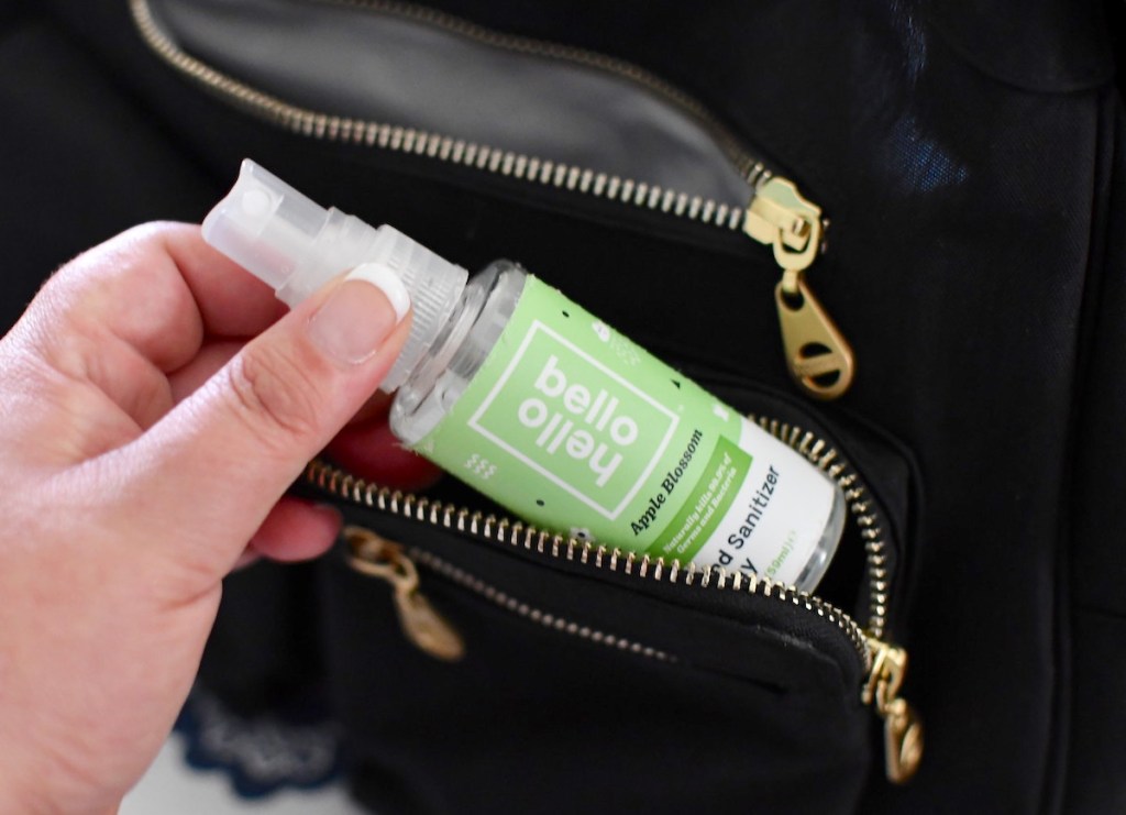 hand holding a bottle of hello bello hand sanitizer from black zipper bag