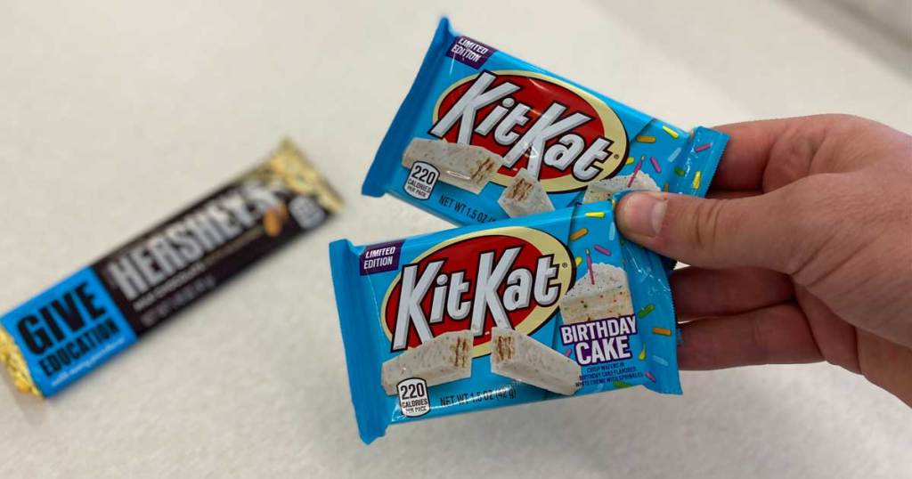 hand holding two chocolate bars and one chocolate bar on counter