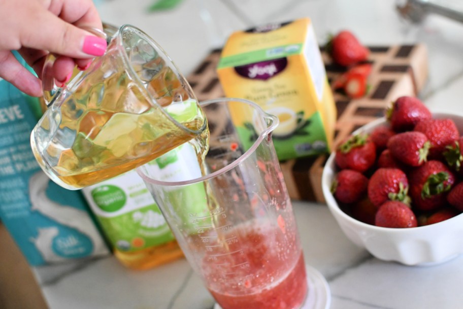 pouring cold iced brewed tea into pink drink