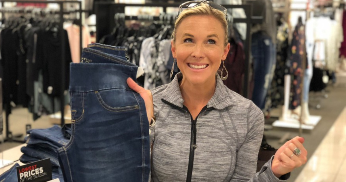 woman holding up jeans in store and smiling