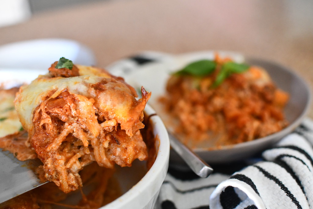 taking slice of million dollar spaghetti out of casserole dish 