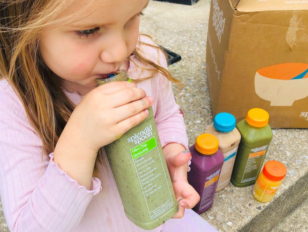 girl holding a green splendid spoon smoothie