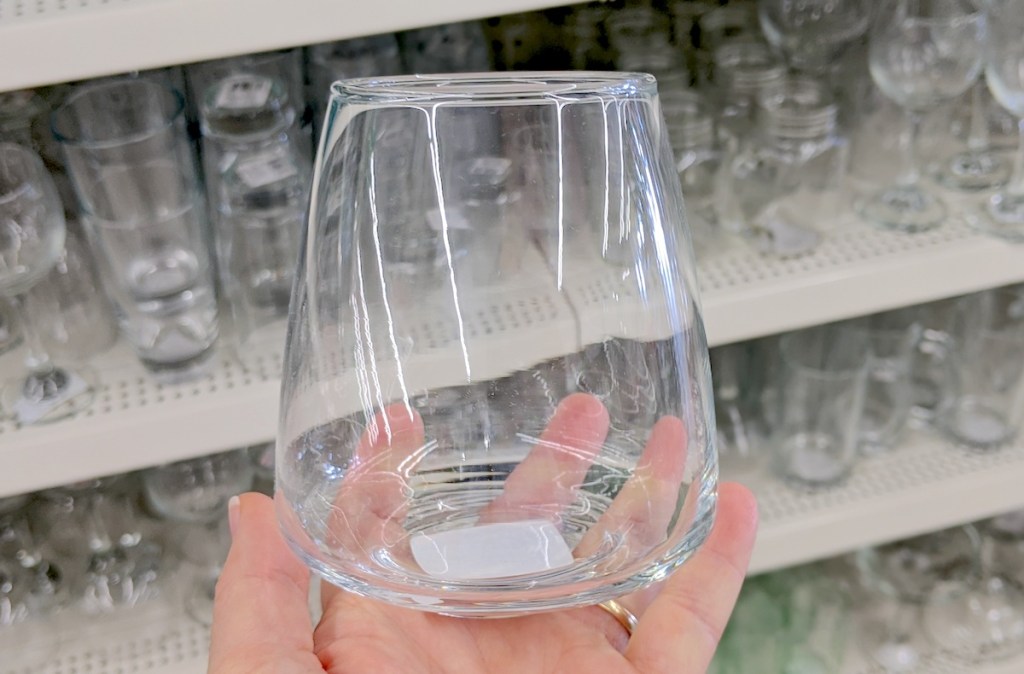 hand holding a clear stemless wine glass in store dish aisle