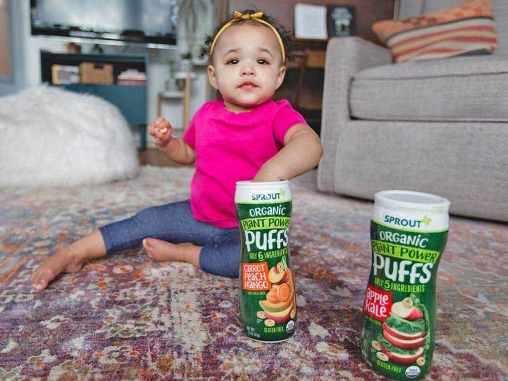 toddler girl sitting on floor eating snacks