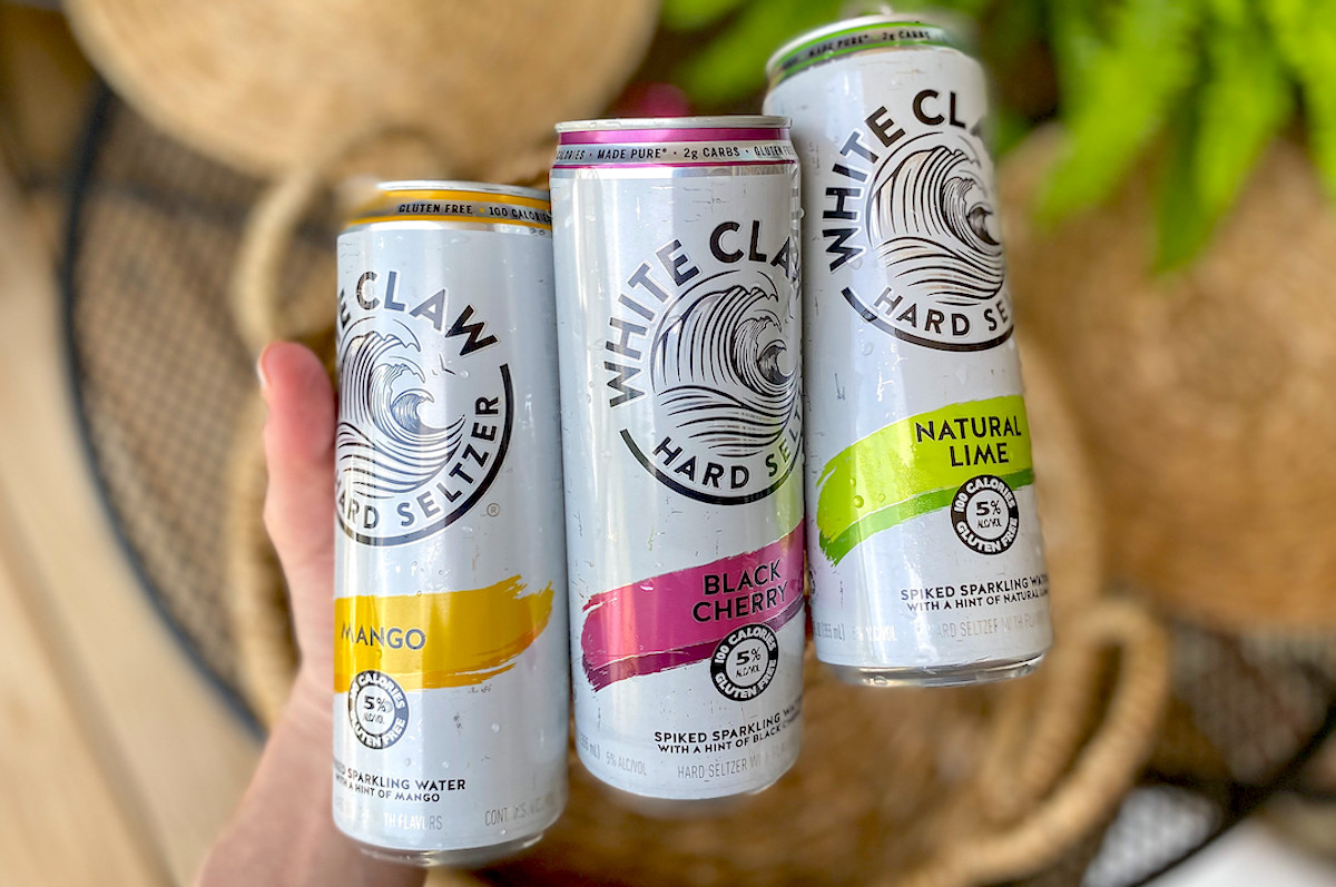 hand holding 3 kinds of white claw cans