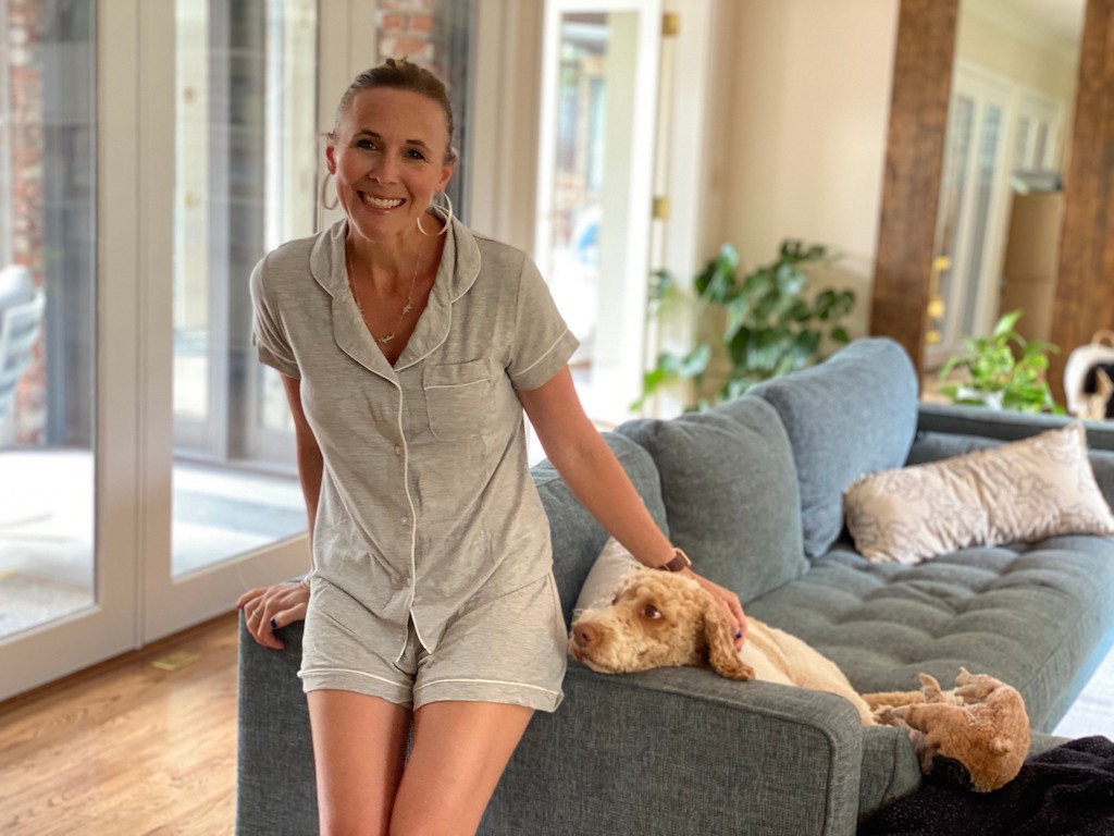 woman wearing pajamas with dog on couch 